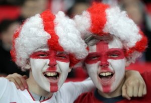 England fans wearing face paint and wigs cheer on their side in the stands